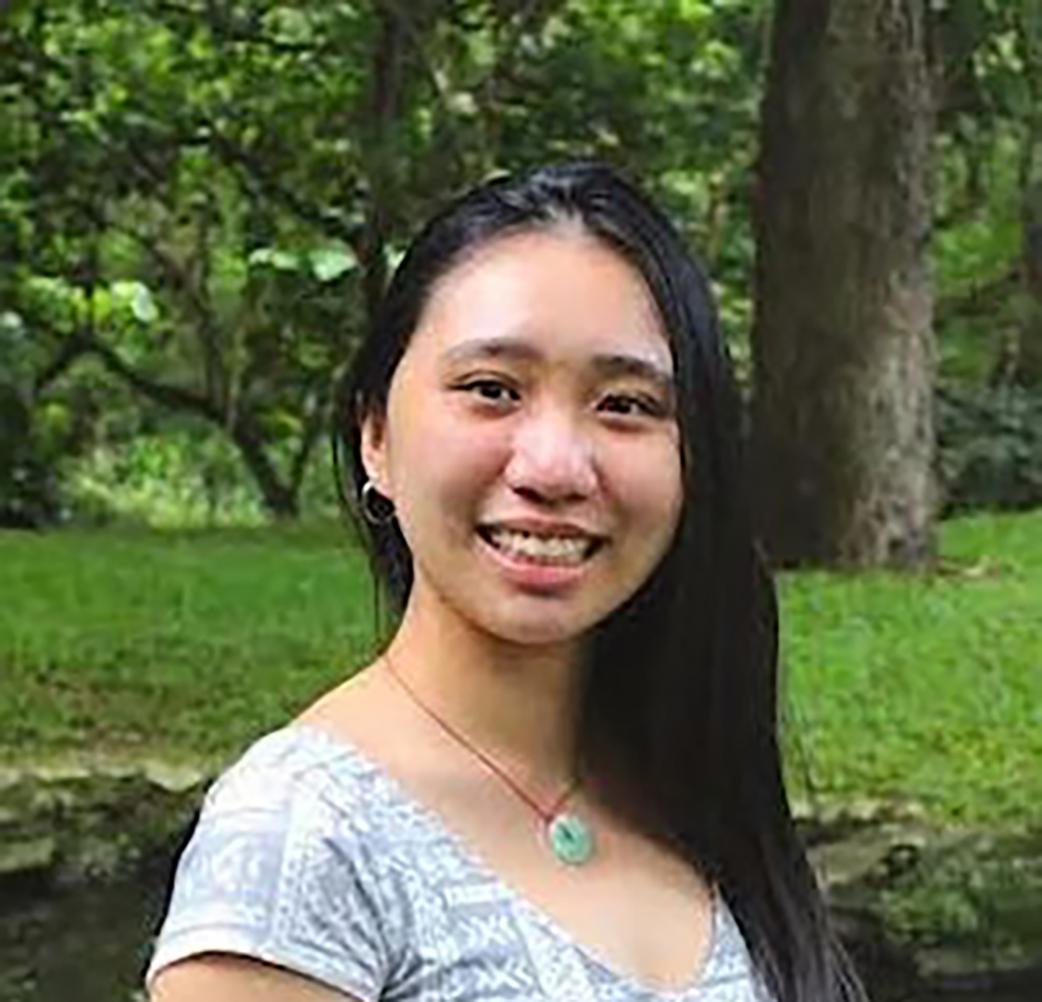 girl posing and smiling in front of grass field