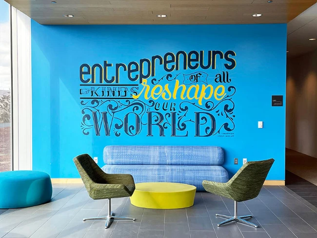 a student-made mural on a blue wall with words that read 'entrepreneurs of all kinds reshape the world' 