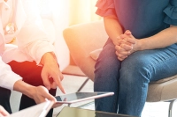 woman pointing at ipad and other woman sitting next to her hands folded together