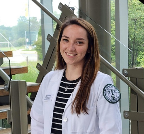 girl smiling wearing white coat with patch on sleeve