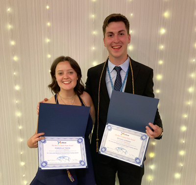 Gabrielle Troch and Michael Romano posting for the camera with their certificates in hand. They are dressed in business professional attire.