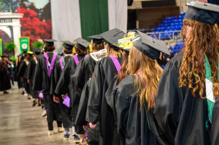 Graduates in academic attire lined up to receive their degrees.
