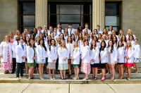 A group of physician assistant students gather in white coats in front of a building with stone columns. Physician Assistant Graduates Achieve Overall Perfect Pass Rate on National Certifying Exam, Exceeding National Average