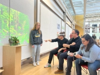 Student presents virtual project while professor wearing virtual reality headset points to the student's project.