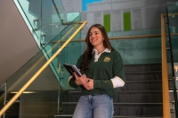 student with notebook in her hand walking down stairs