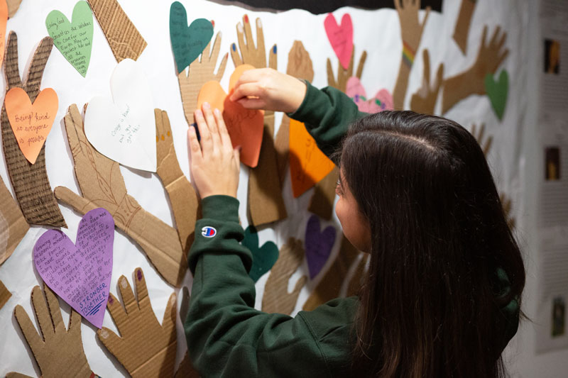 Madison Salano pins paper heart to wall art mural project
