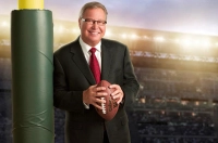 A man holding a football near a goal post