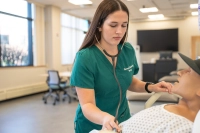 Female nursing student practices the use of a  stethoscope