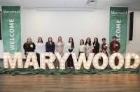 Students gather around lighted letters that spell out MARYWOOD.