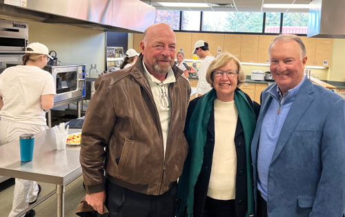 The Cramer family posing for a picture inside a classroom without students working in the background.