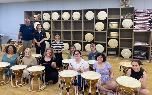 A group photo of music therapy students, including Sophie French, sitting in front of drums.
